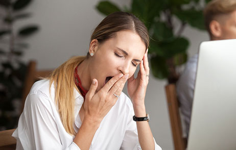 Hypersomnie Frau vor einem Laptop gähnt