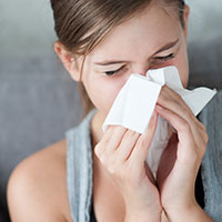 Allergien und Atemwegserkrankungen Frau schnäuzt in ein Taschentuch