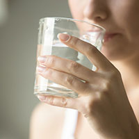 Ständiger Harndrang Frau setzt ein Glas Wasser zum Trinken an