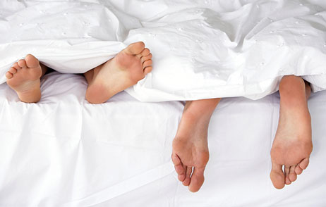 Restless Leg Syndrom Füßen von Mann und Frau ragen aus der Bettdecke