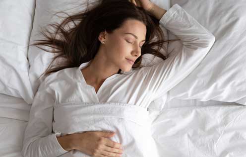 Junge Frau liegt in einem Bett und schläft