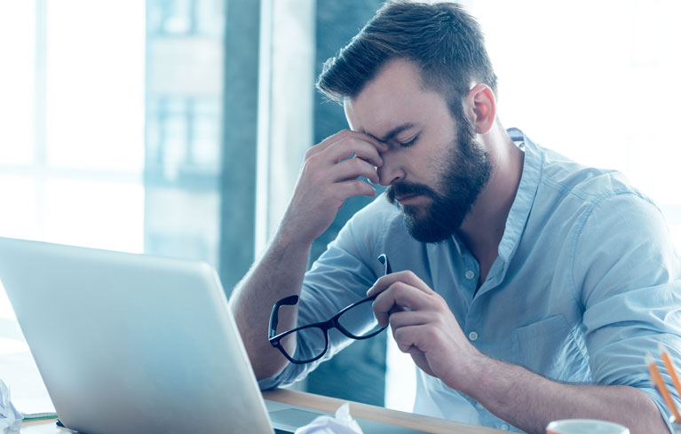 Mann am Bildschirm reibt die Augen